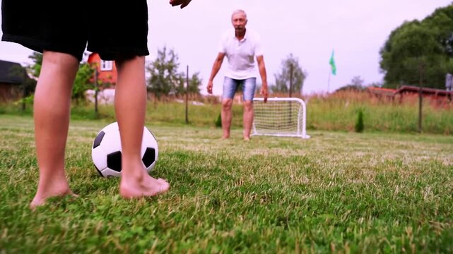 boy with grandfather playing football in the yard of the house