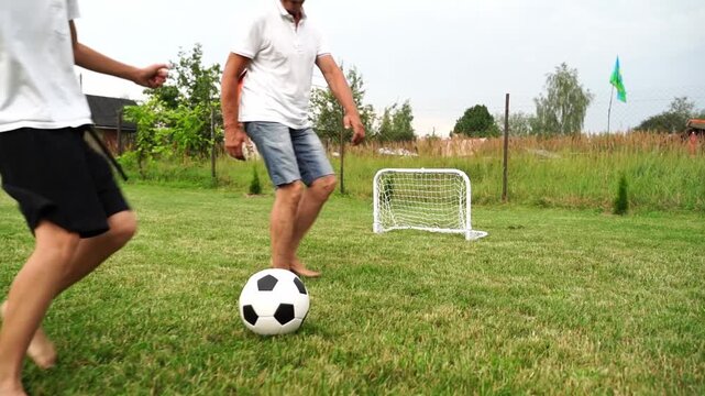 boy with grandfather playing football in the yard of the house