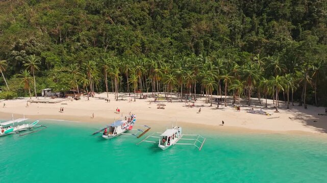 Left sliding drone view shows turquoise bay tourism, El Nido island lifestyle