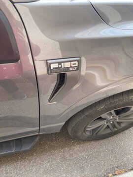 Close-up of the F-150 XLT emblem on the fender of a gray pickup truck