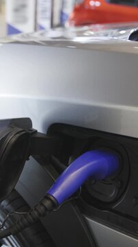 Silver colored electrocar on charge at the charging station indoors