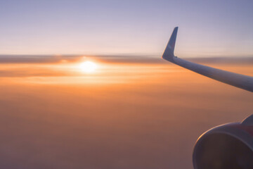 Beautiful background - a plane flying above the clouds and the setting sun on the background, a wing in close-up against the sky. Air travel and tourism, flights and aviation. High quality photo © Vladimir Razgulyaev