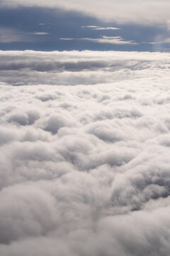 A view of clouds in the sky shows a thick blanket of white puffed clouds stretching widely across the background. The scene captures a sense of height and openness. High quality photo