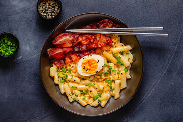 Korean street food - creamy rapokki served with bacon and egg.