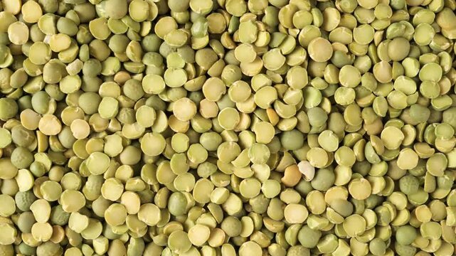 Dry raw green split peas rotating as a texture background for healthy cooking and nutrition concepts.