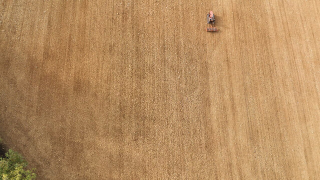 Vintage crawler tractor cultivating agricultural land in rural Tuscany, Italy, an aerial top down view of farming preparing soil for sowing crops