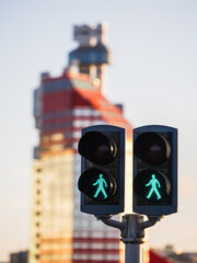 Green pedestrian signals stand in front of a tall building in Gothenburg during sunset in the late afternoon