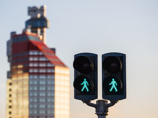 Green pedestrian signals stand in front of a tall building in Gothenburg during sunset in the late afternoon