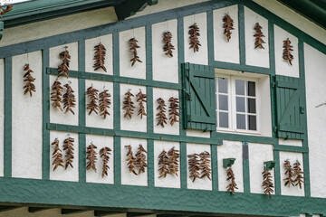 Strings of red Espelette peppers drying on traditional Basque house facade
