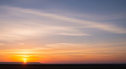 Serene sunrise or sunset spectacle where radiant golden light illuminates a tranquil sky, casting warm hues of orange, yellow, and blue across the horizon, creating a peaceful natural panorama