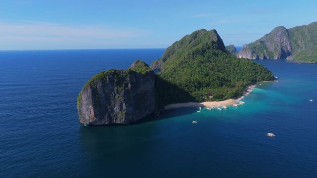 Cinematic aerial drone shot of the iconic Helicopter Island (Dilumacad Island) featuring towering limestone cliffs and turquoise waters in El Nido, Palawan, Philippines