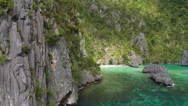High-angle drone shot of the dramatic limestone karst formations and lush vegetation on Helicopter Island in El Nido, Palawan. aerial footage of the Philippine coast