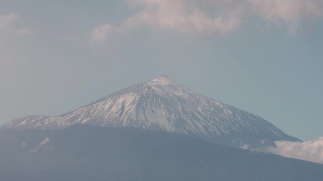 Daytime timelapse view of Mount Teide volcano from Mirador del Pris in Tenerife, Canary Islands. Snow-capped peak under clear blue sky.