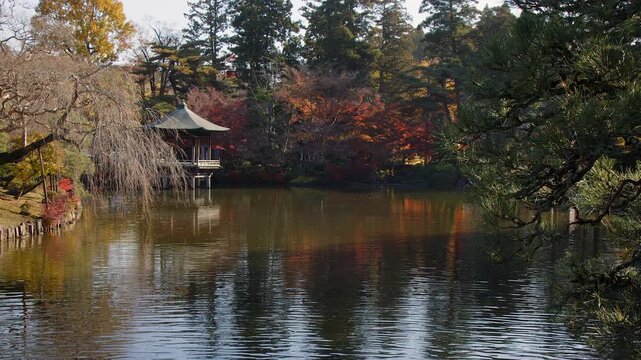 Serene scene: Ukimido pavilion on pond in autumn Japanese nature park