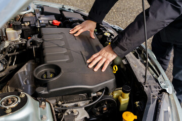 Obraz premium Hands on a car engine under an open hood during inspection, maintenance, or roadside check, showing vehicle condition and engine compartment details.