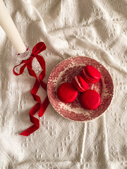 Candle with red ribbon and macaroons on a vintage plate