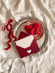 Vintage envelope and candle with red ribbon on a silver tray. Valentine`s Day aesthetic