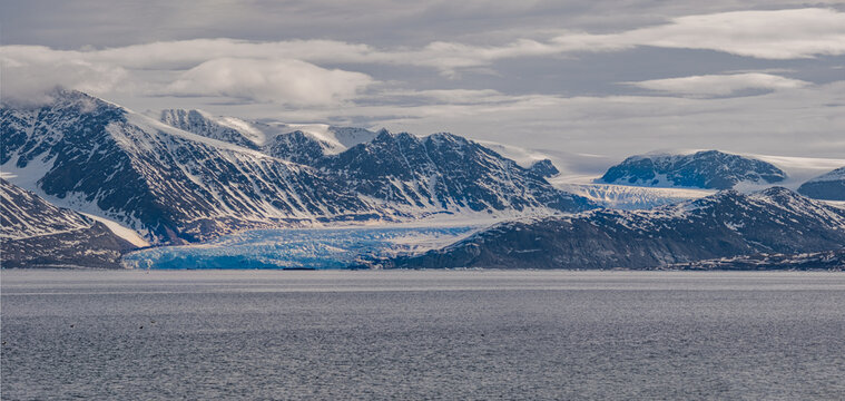 Spitzbergen, Svalbard, Norwegen: Arktische Gebirgslandschaft spiegelt sich im stillen Wasser des Magdalenefjorden mit Treibeis unter strahlend blauem Himmel.