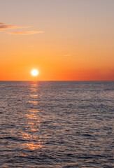 Obraz premium Sonnenuntergang über dem Meer am Horizont, minimalistische Meereslandschaft bei goldener Stunde, ruhiger Ozean unter orangefarbenem Himmel, maritime Naturaufnahme, Abendstimmung.
