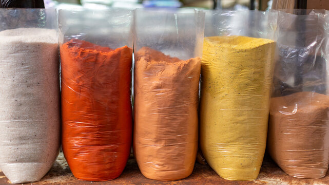 Assorted ground spices including salt, chili powder, achiote (annatto), turmeric and cumin in plastic bags at a market stall in Santa Ana, El Salvador. Vibrant Central American food background.