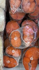 Fresh coho salmon steaks wrapped in plastic on seafood market display  