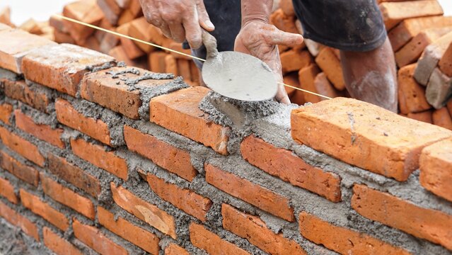 Close-up of hands of Skilled bricklayer laying bricks with precision