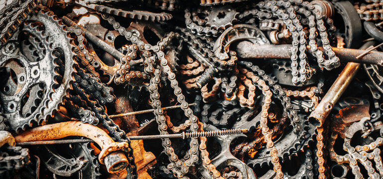A detailed macro study of industrial decay: close-up textures of rusty chains, gears, and sprockets in a scrap metal pile, remnants of machinery from an abandoned factory yard. High quality photo