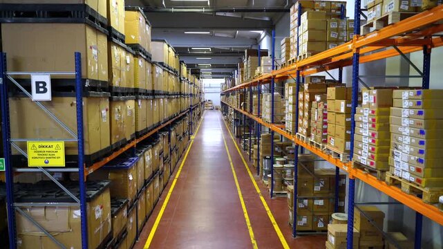 Drone footage moving backwards revealing a vast distribution center filled with cardboard boxes on high shelves. Concept of global e-commerce business, supply chain, and industrial storage.