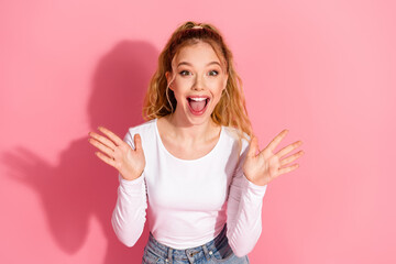 Young woman expressing excitement with cheerful gesture against a pink background, showcasing...