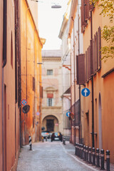 Naklejka premium Wander through narrow, sunlit alleys of Bologna, where warm orange walls echo rich history. Delight in the vibrant atmosphere, spotted with quaint shops and inviting cafes