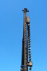 青空の下で建設現場の基礎工事に用いられる巨大なスクリュー型の掘削機