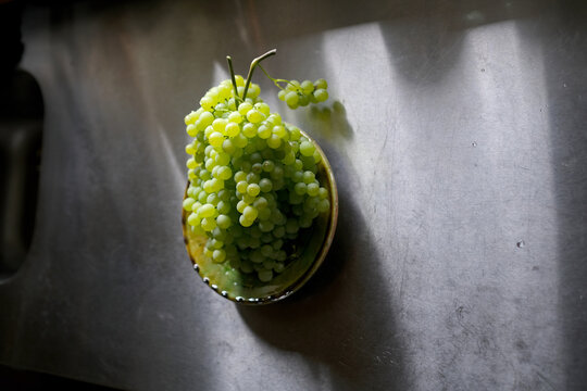 Fresh Small Green Grapes in a Decorative Bowl on a Stainless Steel Surface
