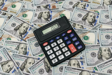 Fototapeta premium One hundred dollar bills next to calculator on flat surface. Finance, budgeting and accounting concept.