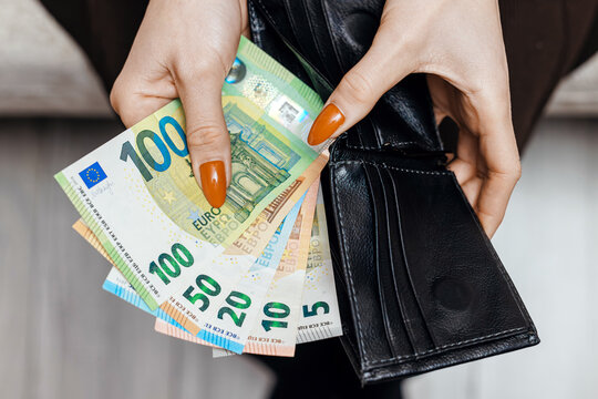 Faceless woman holding an open wallet with euro banknotes inside. Finance, wealth and money management concept.