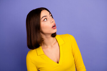 Fototapeta premium Young chic model in a bright yellow top looks up with curiosity against a purple background for fashion lifestyle and shopping promotion