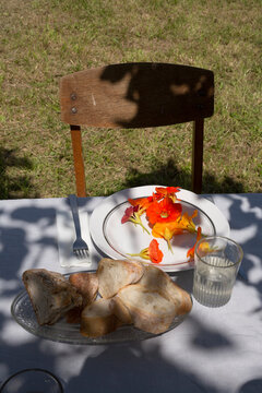 Rustic summer dinner table in the countryside with fresh bread and nasturtium flowers