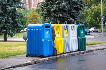 Colorful recycling bins aligned on roadside in city park area showing waste separation environmental responsibility and sustainable urban living