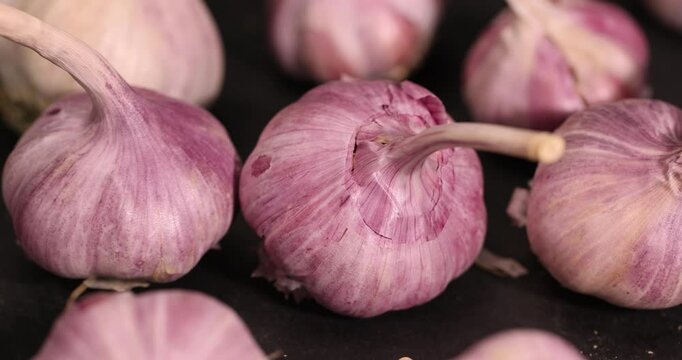 ripe garlic is scattered on a black table in the kitchen, garlic spices are on a black slate board in the kitchen over cooking