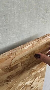 Oriented chipboard close-up. A woman's hand touches a osb wooden board made of sawdust. Building material for roughing