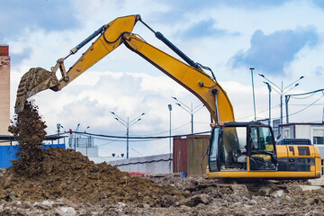 Excavator loading and moving soil at a construction site, heavy machinery performing earthworks for...