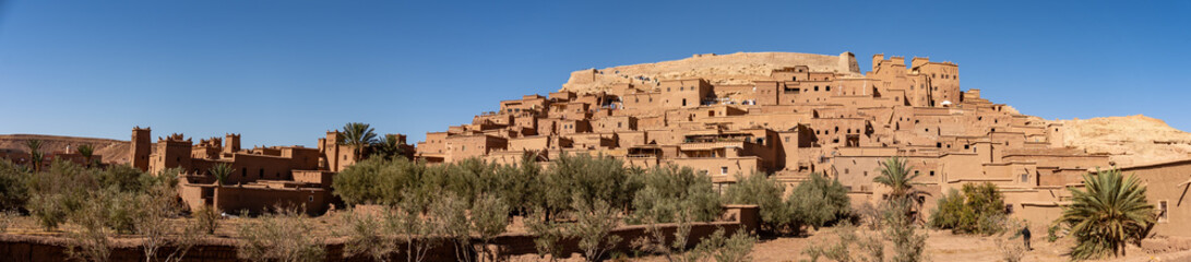 Panorama of the fortified city of Ait Benhaddou, Morocco, at the base of a hill, surrounded by lush vegetation © Angela