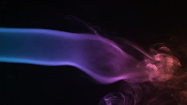 Dynamic streams of vibrant, multicolored smoke billow and swirl against a deep black background, creating an ethereal and mesmerizing abstract display. Hues of electric blue, rich purple, luminous pin