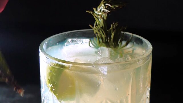 Delicious alcoholic cocktail made with jin tonic and ice in glasses for relaxing at night and refreshing in the summer. Spices and green lime for flavor. Bartender and bar. Rosemary burns with fire