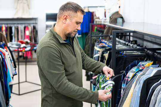 Man browsing clothes at vintage thrift shop, second-hand stylish store