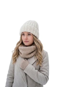Young woman in beige knitted winter hat, snood scarf, and gloves, wearing a light gray wool coat, isolated on white background