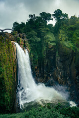 Obraz premium Waterfall cascading down rocky cliff in lush green forest. Weinia waterfall in Meghalaya, india.