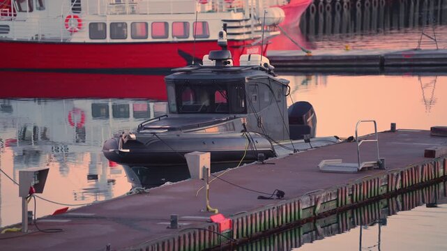 REYKJAVIK, ICELAND - JANUARY 31 2026: Security camera mounted on a small black boat at the harbor with wooden pier and vessels in the background, 4K.