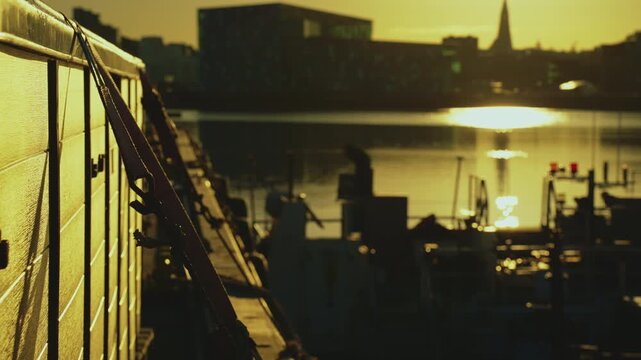 Cargo box secured with straps on a pier with blurry Reykjavik skyline and Harpa at sunrise, 4K.