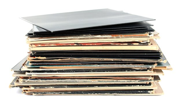 A stack of old, well-used vinyl record covers and sleeves, some black, some with colorful designs, and various states of wear