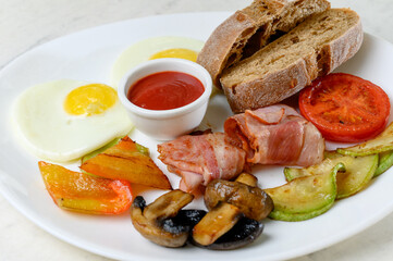 English breakfast with fried eggs, fried bacon, mushrooms and vegetables